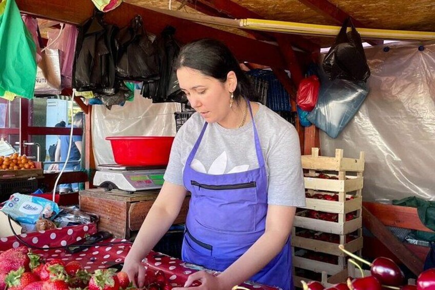 A person in a purple apron working with strawberries at a market stall. 4
