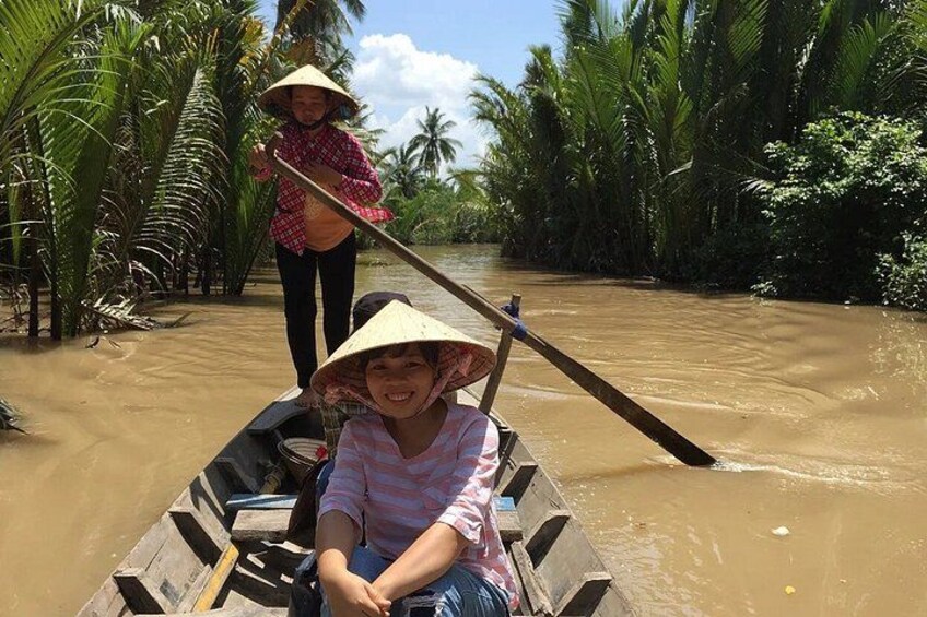 Two people in a narrow waterway, one steering a boat and the other standing behind. 2