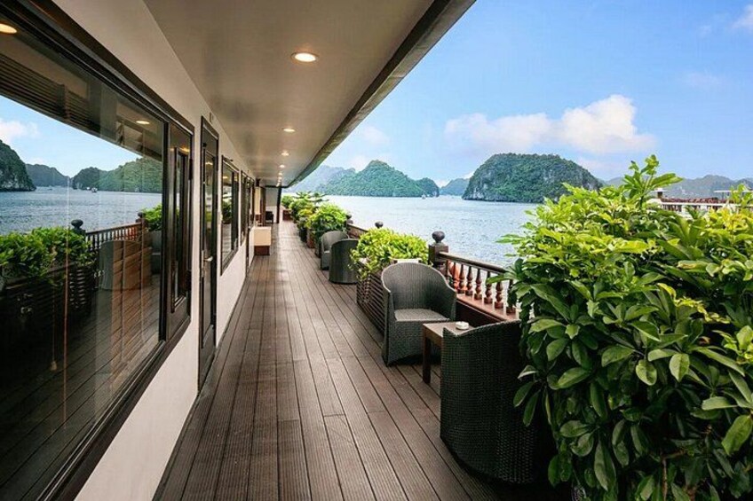A wooden deck with outdoor furniture overlooking a body of water and green hills. 1