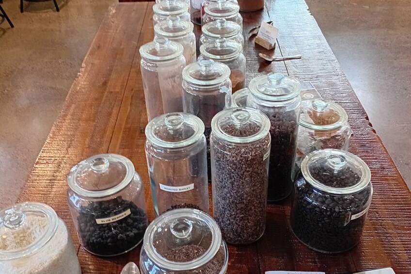 A wooden table with multiple glass jars containing various grains and seeds. 2