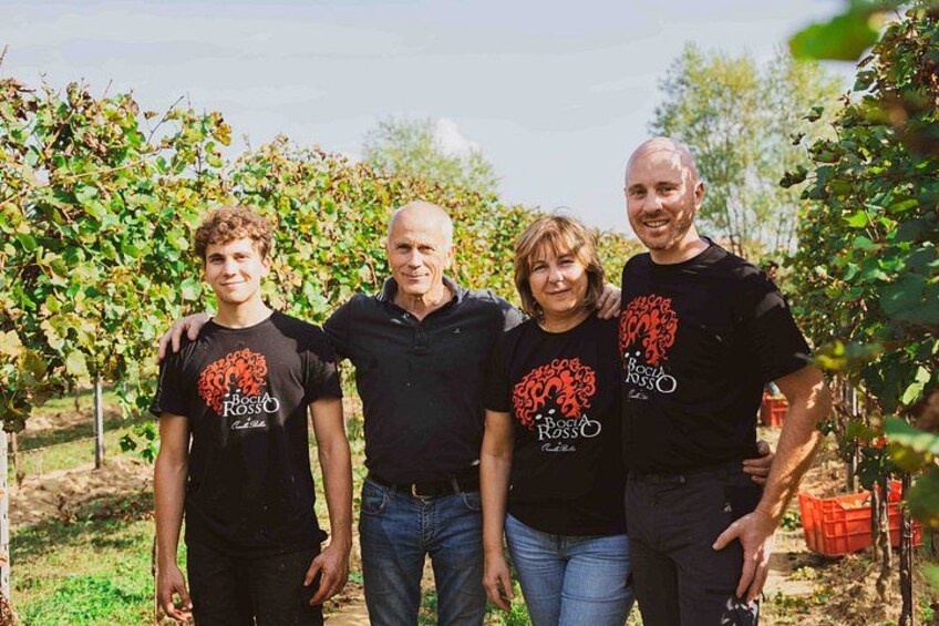 Four people standing in a vineyard with rows of grapevines. 5