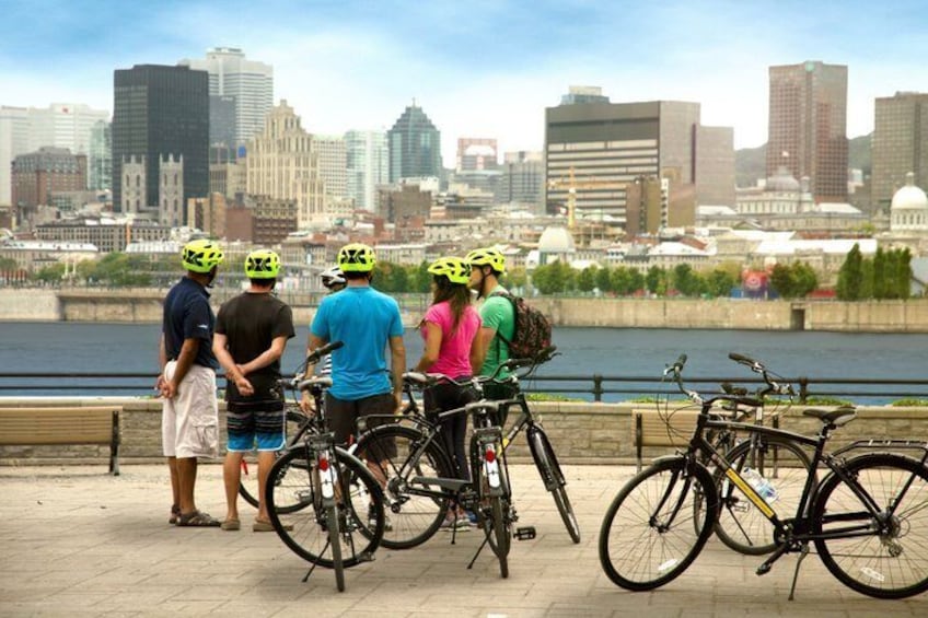 A group of people with bicycles by a waterfront with a city skyline in the background. 4