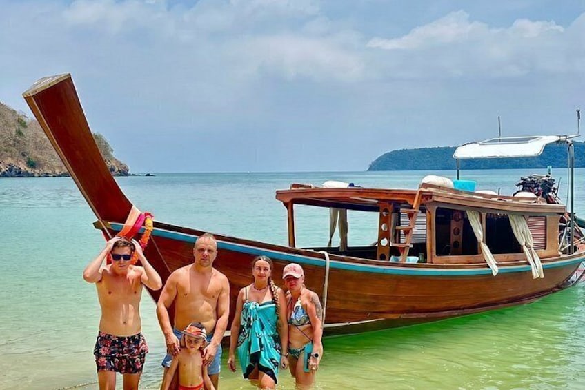 A wooden boat with people standing beside it on a beach. 3