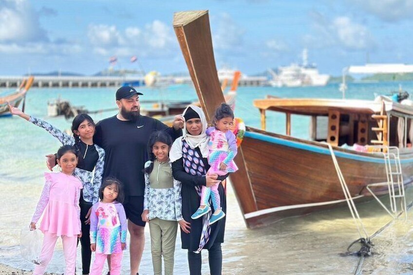 A family on a beach with a boat in the background. 4