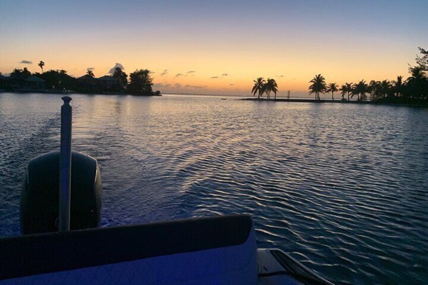 A boat on calm water with a sunset and palm trees in the background. 3