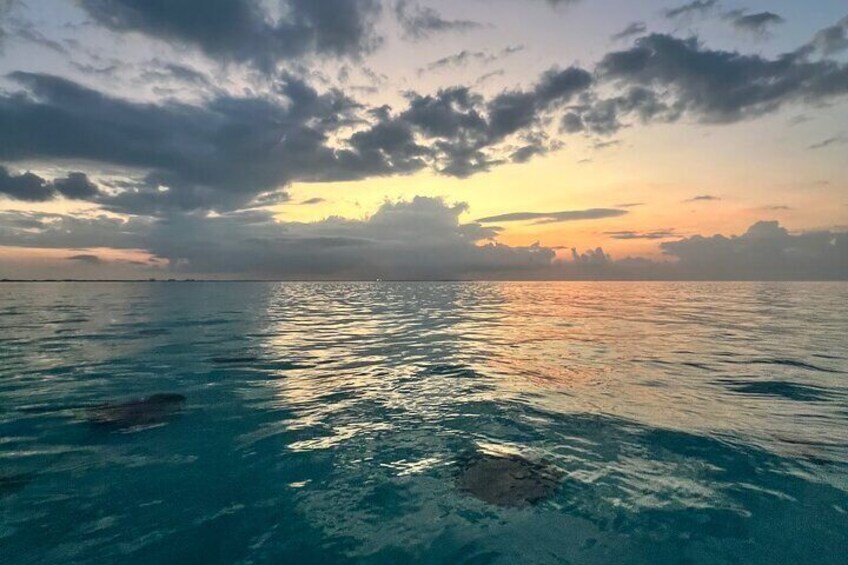 A calm sea at sunset with clear skies and distant land. 2