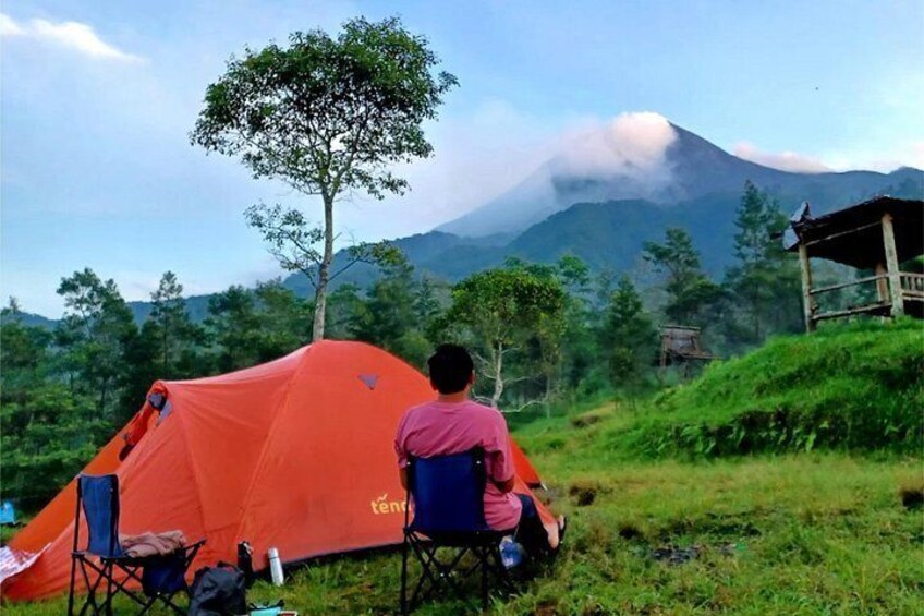 A person sitting in front of a tent with a mountain in the background. 3
