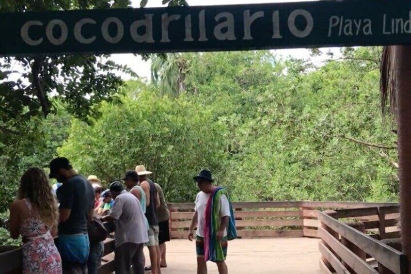 A wooden bridge with a sign reading 'cocodrario Playa Lind.' 3