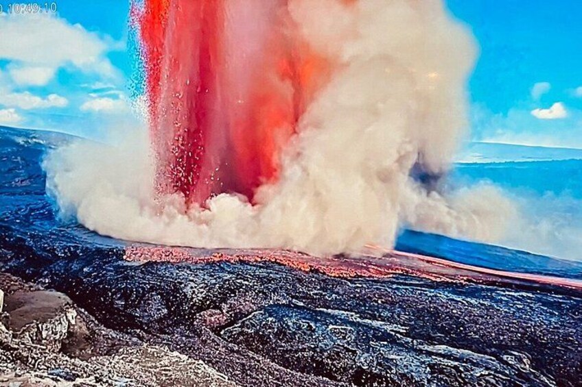 A volcanic eruption with lava flowing and steam rising. 1