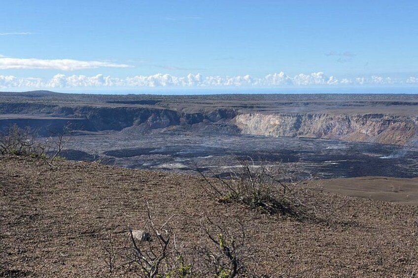 A vast canyon landscape with sparse vegetation and distant hills under a clear sky. 2