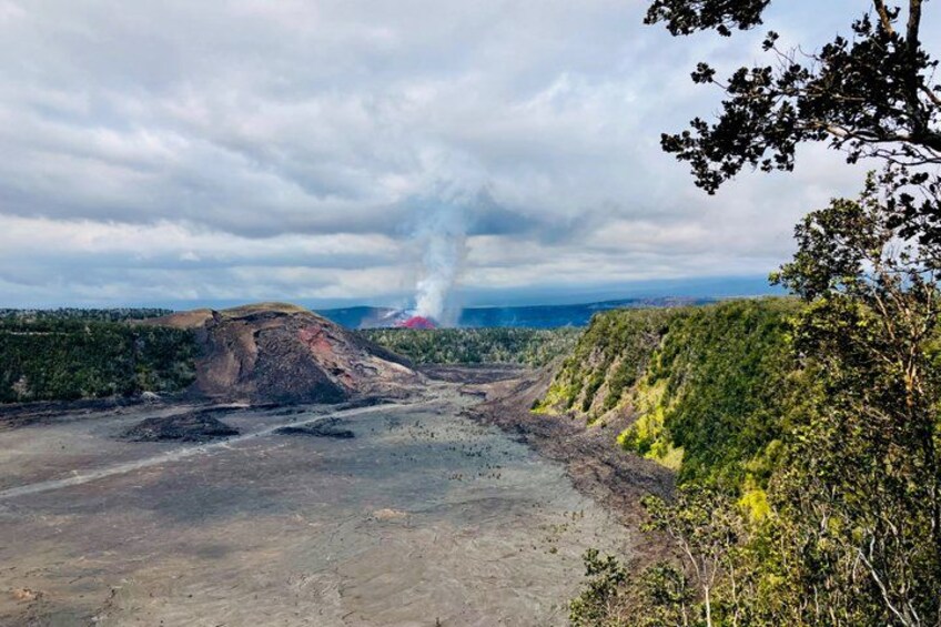 A volcanic landscape with a crater emitting smoke, surrounded by forested hills. 2
