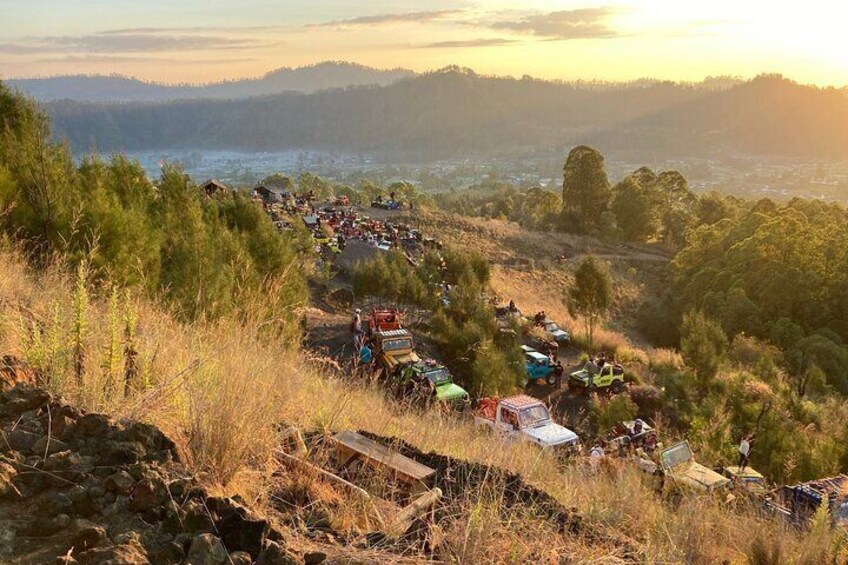 A rural area with a long line of vehicles parked on a hillside. 3