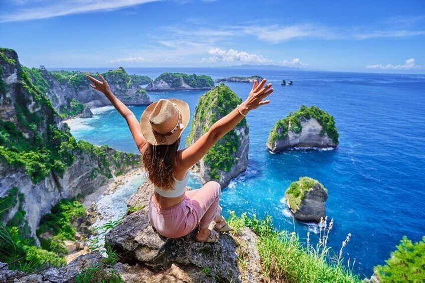 A person sitting on a cliff overlooking a coastal landscape with cliffs and greenery. 2