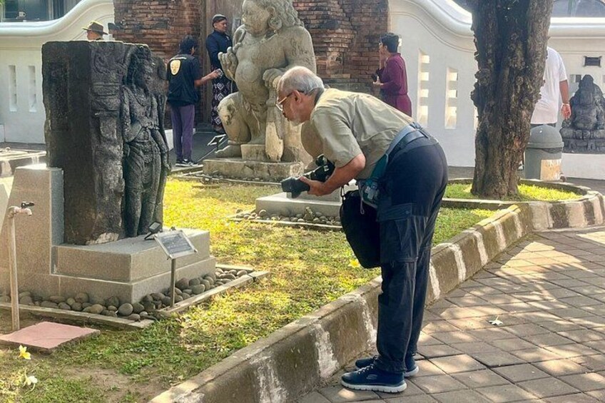 A person taking a photo of a statue in a park. 2