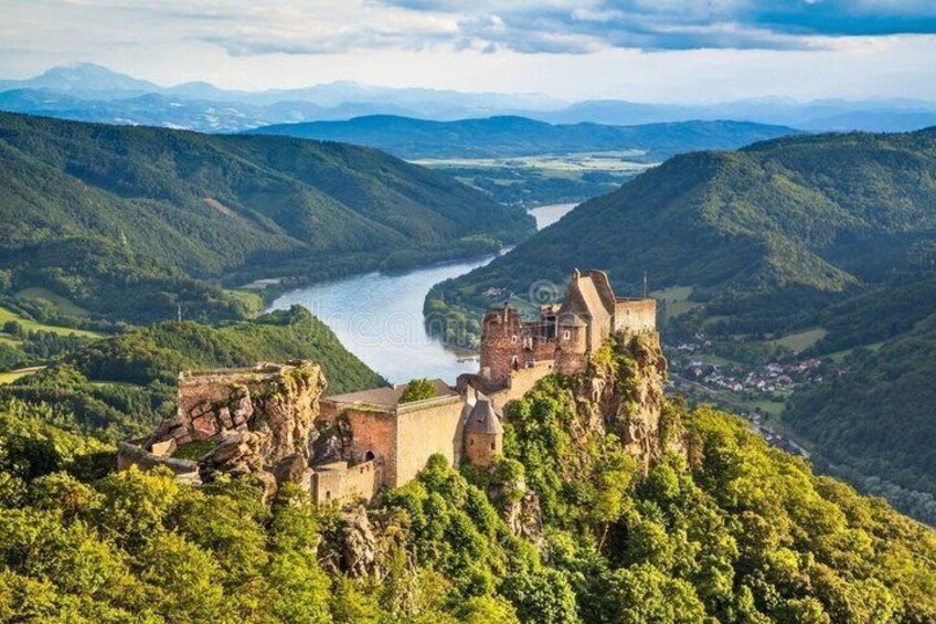 A castle on a hill overlooking a river, surrounded by lush green hills. 2