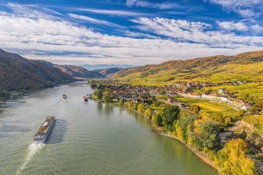 A river with boats, a town on the riverbank, and surrounding hills. 4
