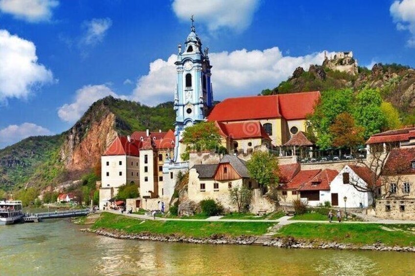 A historic town with a prominent church, a castle on a hill, and a river. 3