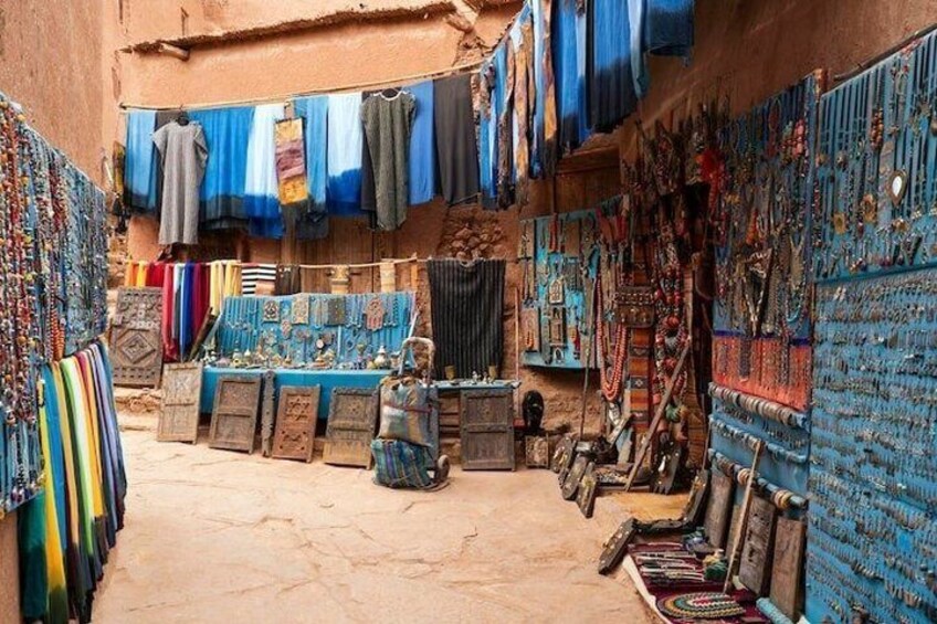A narrow alley with a variety of textiles and jewelry displayed on walls and tables. 3