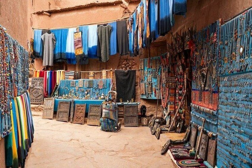 A market with colorful textiles and jewelry displayed on tables and walls. 3