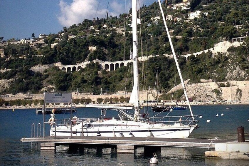 A sailboat docked at a pier with a mountainous backdrop. 2