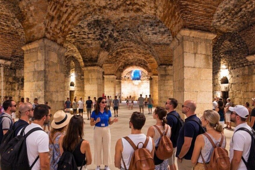 A group of tourists inside a historical building with stone arches and columns. 2