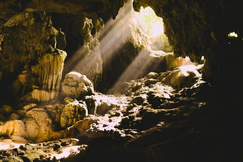 A cave with stalactites and stalagmites, illuminated by natural light. 1