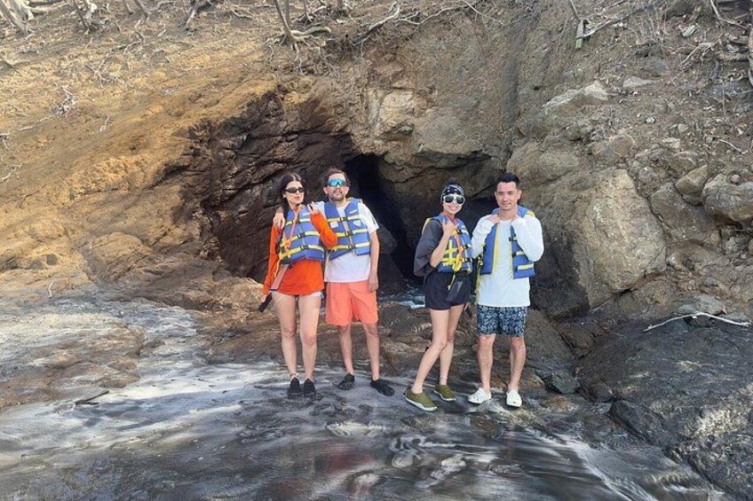 Quatre personnes se tiennent devant l’entrée d’une grotte rocheuse. 2