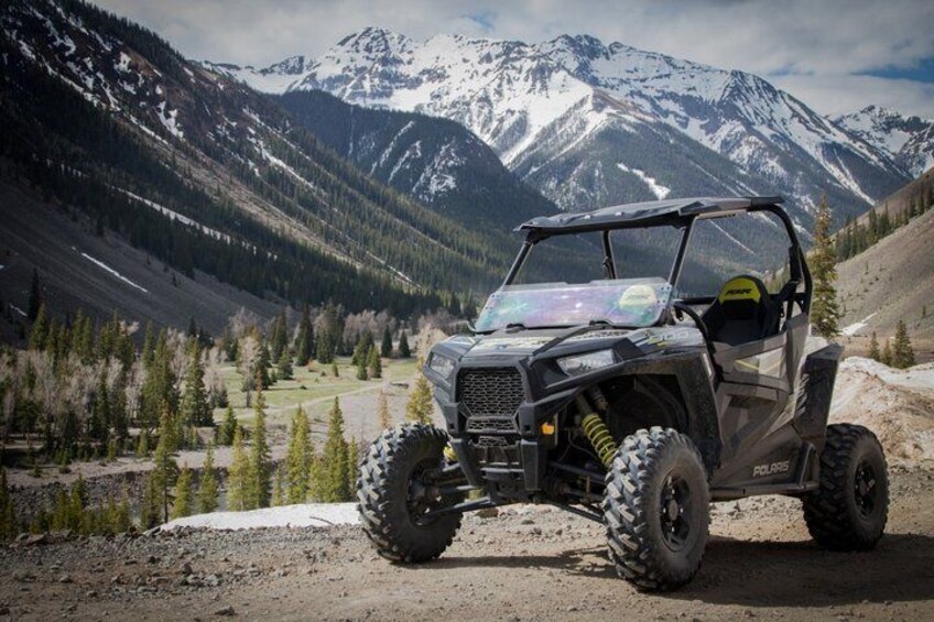 A Polaris ATV in a mountainous terrain with snow-capped peaks in the background. 3