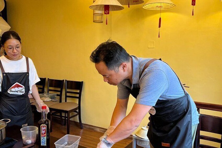 A person preparing food at a table with a bottle and a plastic container. 5