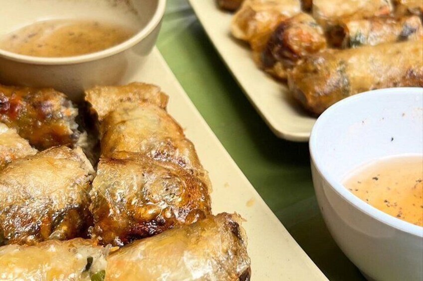 A plate of fried spring rolls with dipping sauce. 2