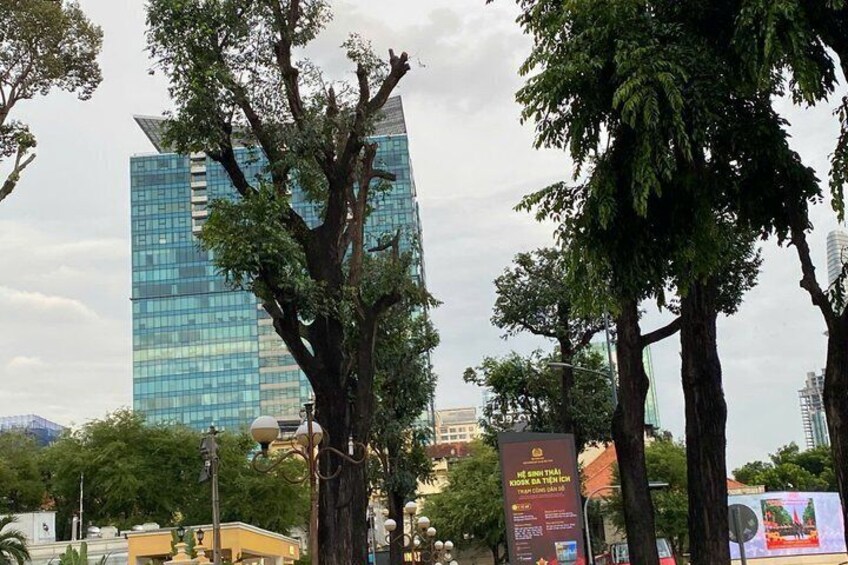 A cityscape with modern buildings, large trees, and a street lamp. 2