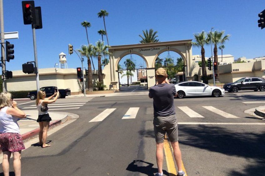 A street intersection with palm trees, a white sports car, and a pedestrian crossing. 3