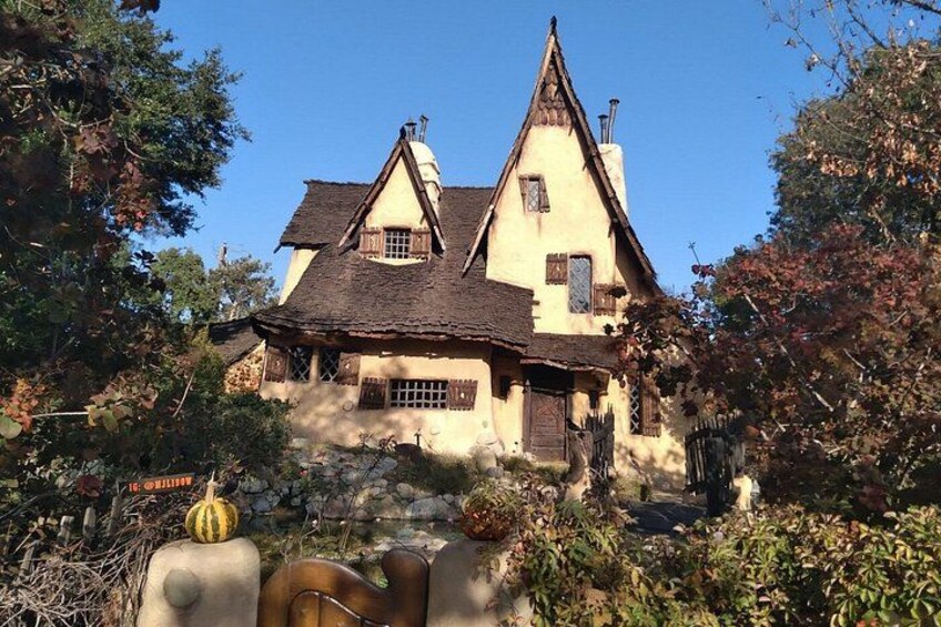 A quaint, traditional house with a steeply pitched roof, surrounded by lush greenery and a stone wall. 4