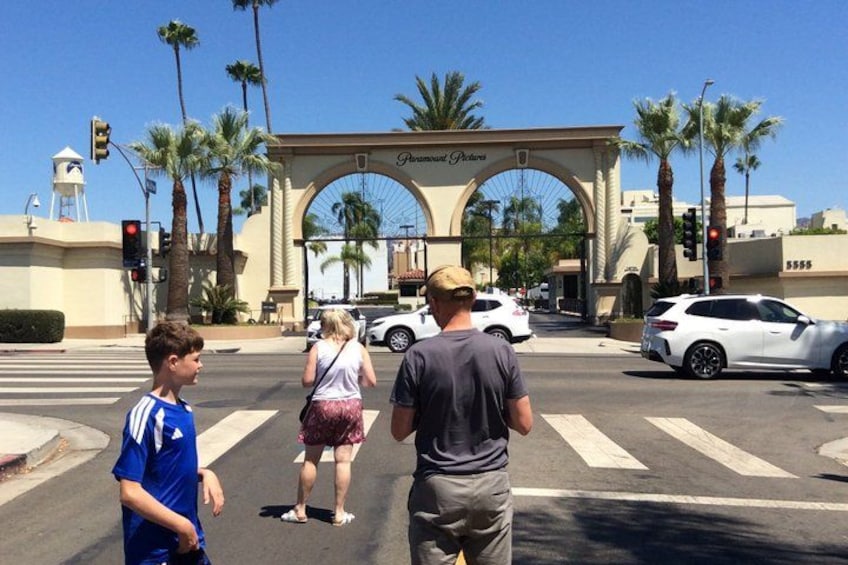 A pedestrian crossing with palm trees and a large archway in the background. 2