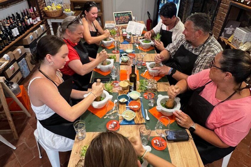 A group of people engaged in a cooking activity around a long table with various ingredients and cooking utensils. 1