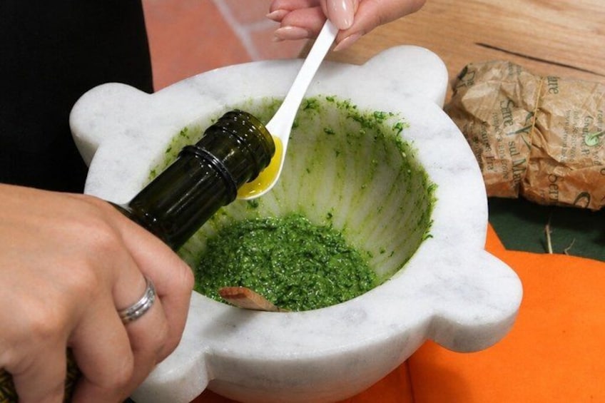 A person using a mortar and pestle to grind green herbs. 2