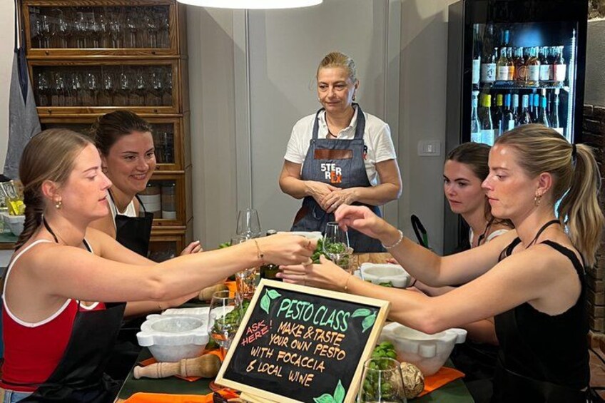 A group of people at a table with a sign that reads 'Pesto Class'. 2
