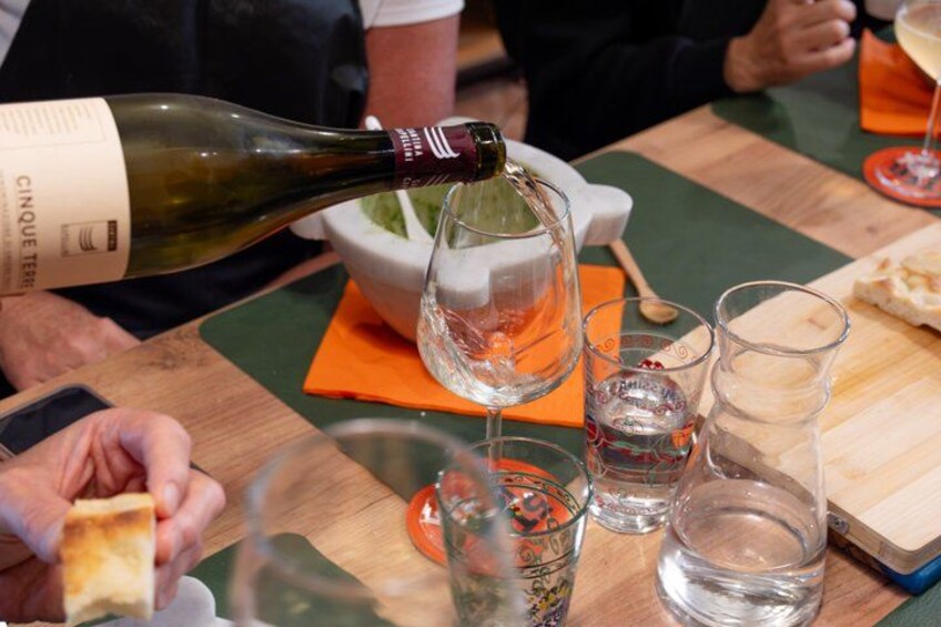 Una persona sirve vino en una copa, un plato de comida y varios vasos sobre una mesa. 5