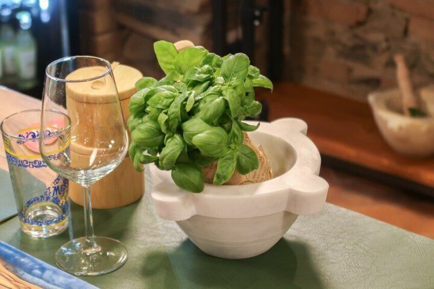 A kitchen counter with a glass of wine, a wooden mortar, and fresh basil. 4