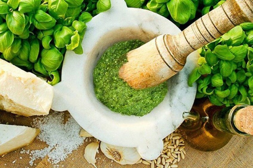 Un mortaio con pestello, pesto verde, foglie di basilico, formaggio e sale. 4