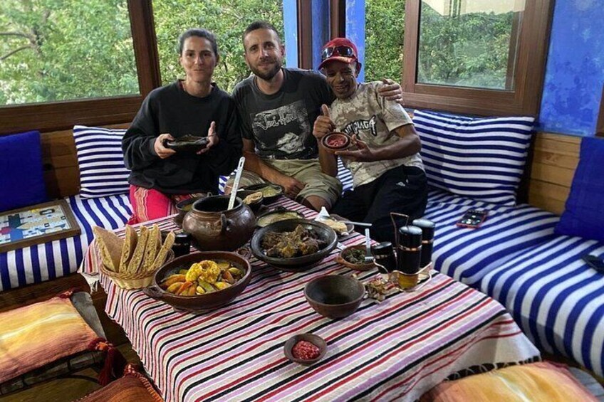 Three people sitting on a striped couch with a table full of food and drinks in front of them. 1