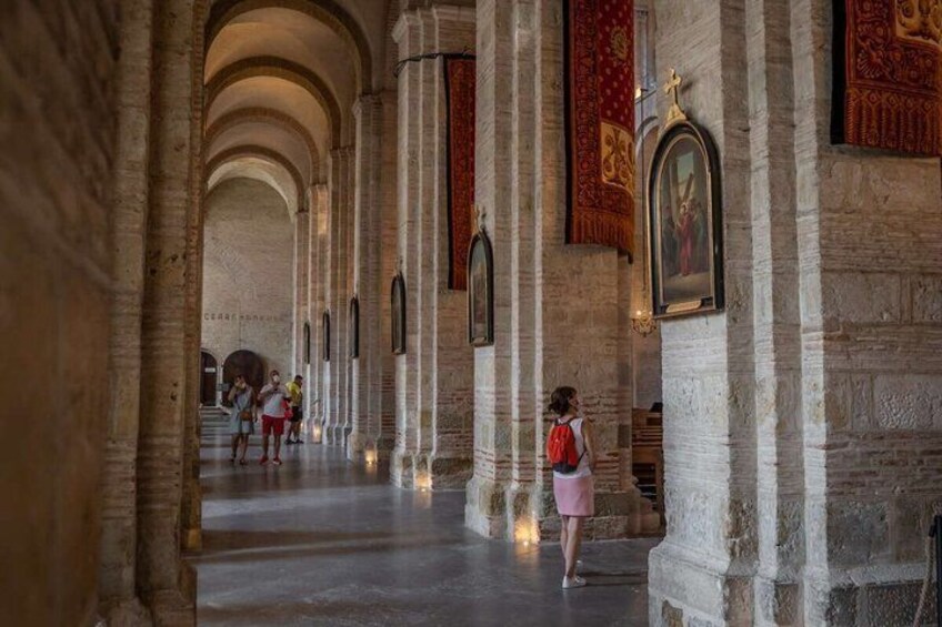 A cathedral interior with arched ceilings, stone columns, and religious paintings. 5