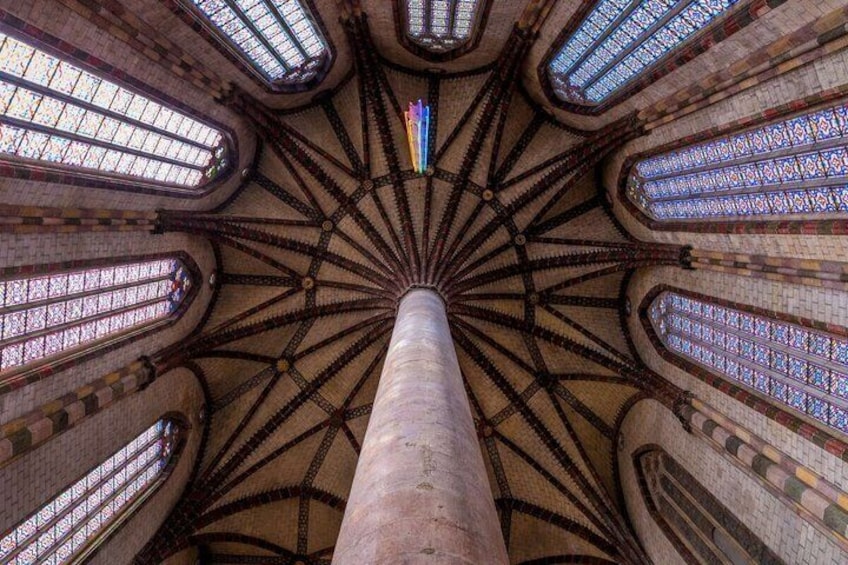 A cathedral's interior with a central column, arched windows, and a star-shaped ceiling design. 2