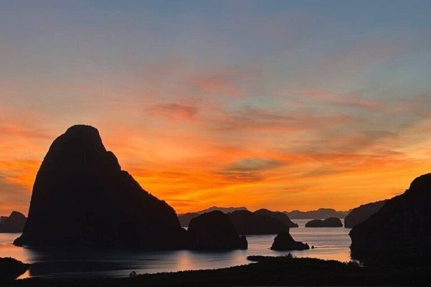 A sunset over a coastal landscape with prominent rock formations. 1