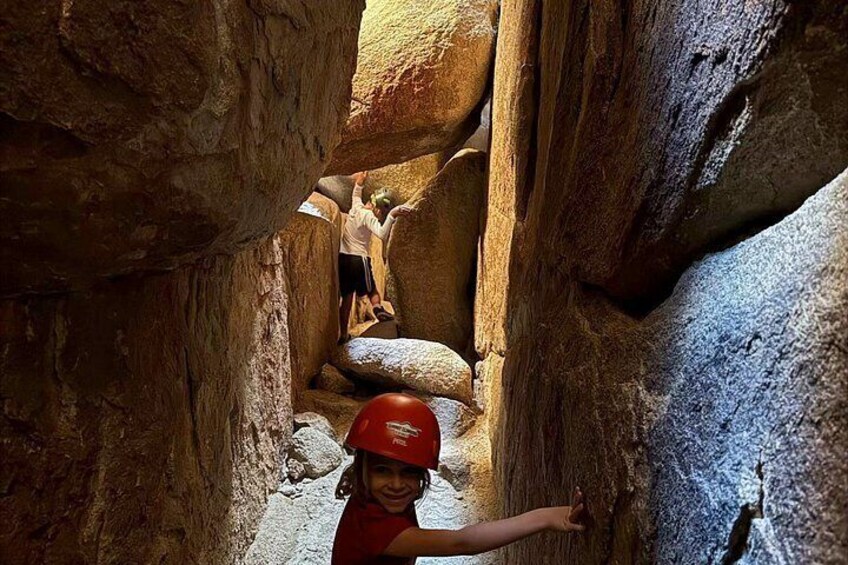 A person in a red helmet climbing a rocky canyon wall. 5