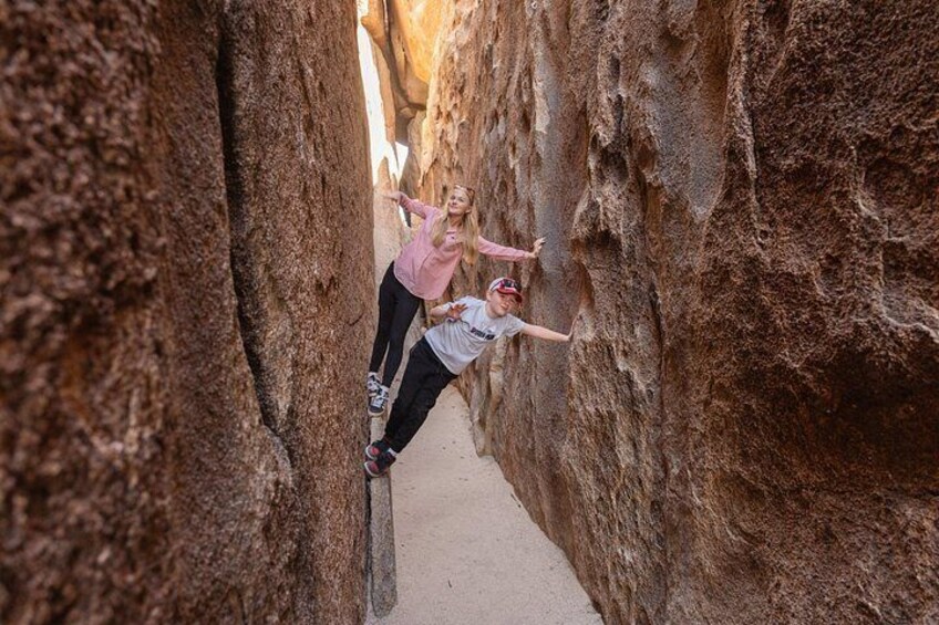 Two people climbing a narrow rock formation. 3