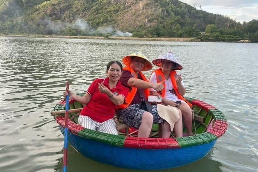 Three people in a boat on a calm river, surrounded by greenery and hills. 2