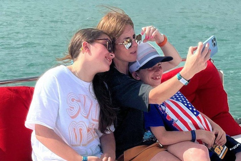 Three people on a boat with a water background. 5