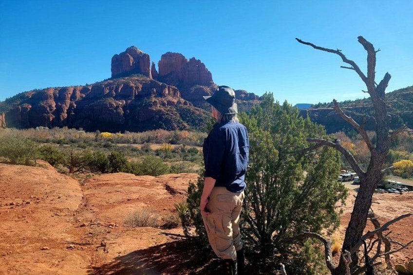 A person standing in a desert landscape with red rock formations in the background. 4