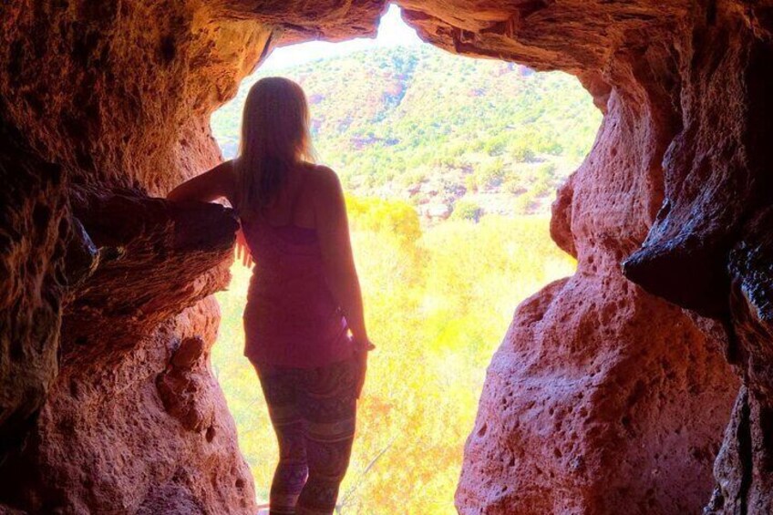 A woman gazes outward onto the beautiful landscape from within a cave formation in Sedona 2